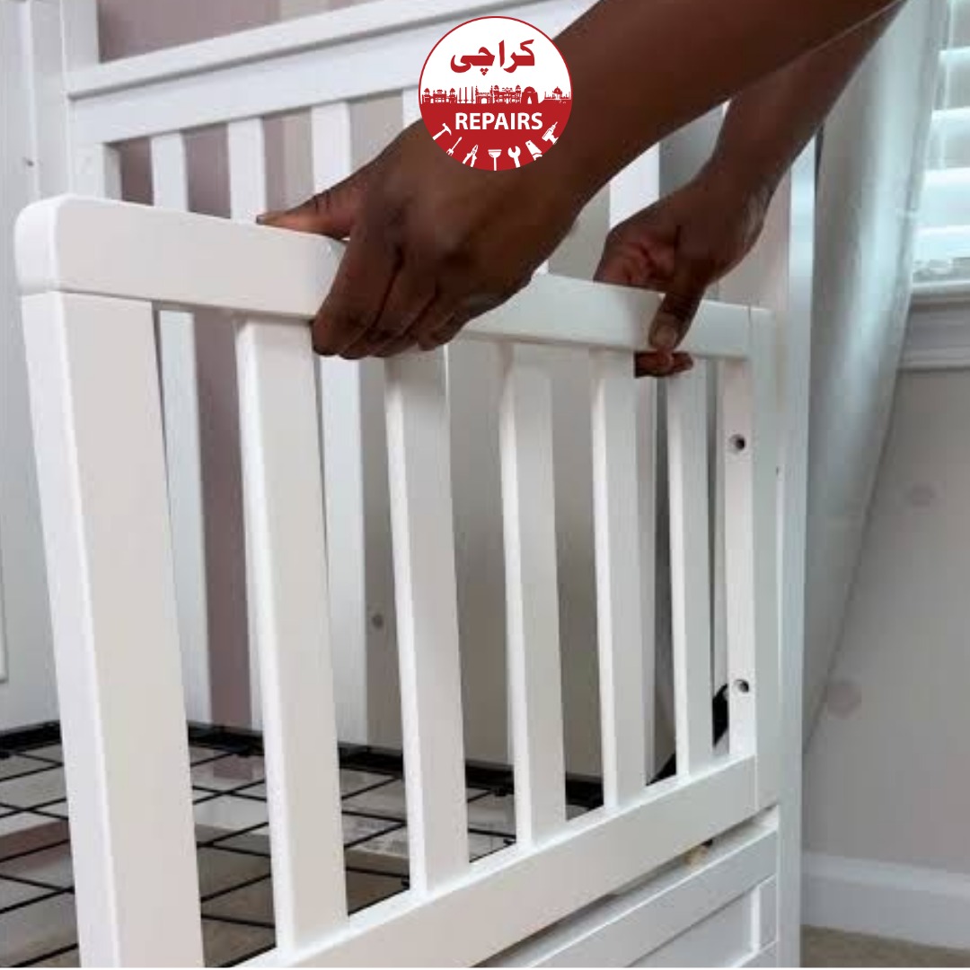 Carpenter repairing and reinforcing a wooden baby cot frame in Karachi