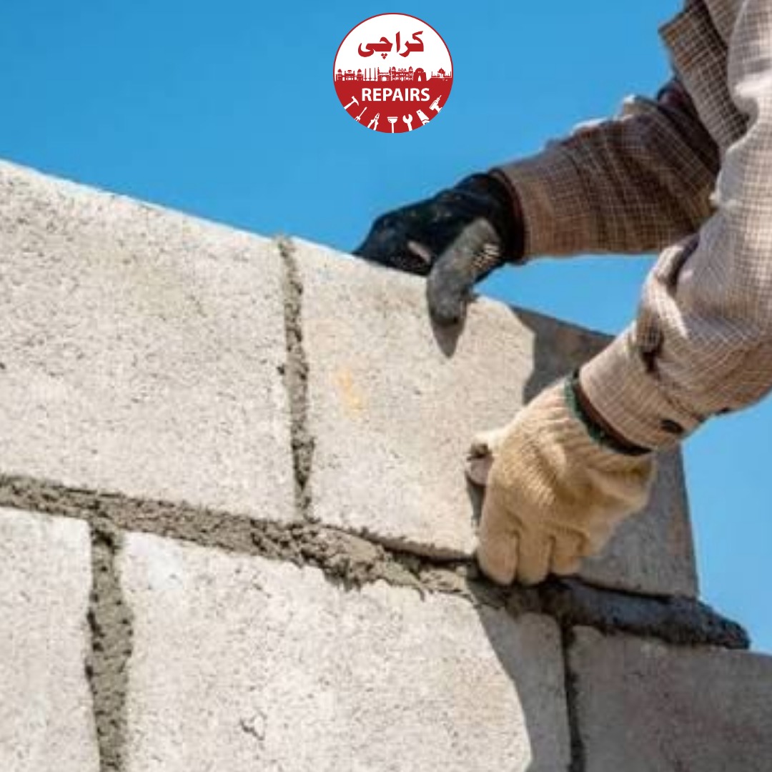 Masons constructing a heavy-duty load-bearing concrete block boundary wall in Karachi