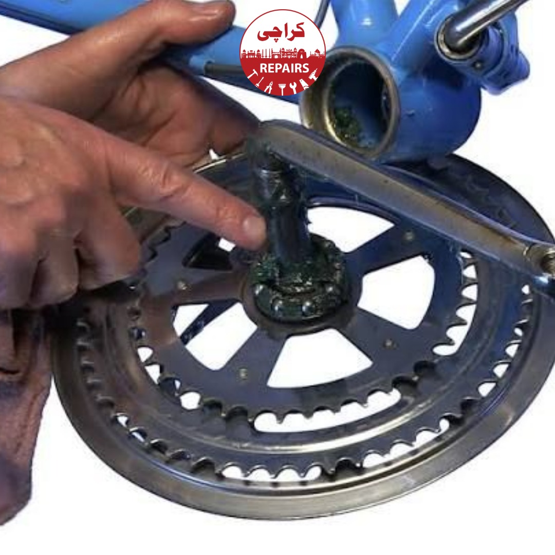 Expert bike mechanic installing a new gear crankset onto a bicycle frame