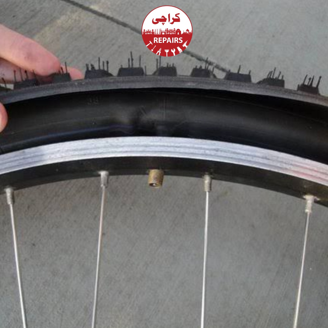Bicycle mechanic inspecting the tire casing and rim tape before inner tube replacement in Karachi