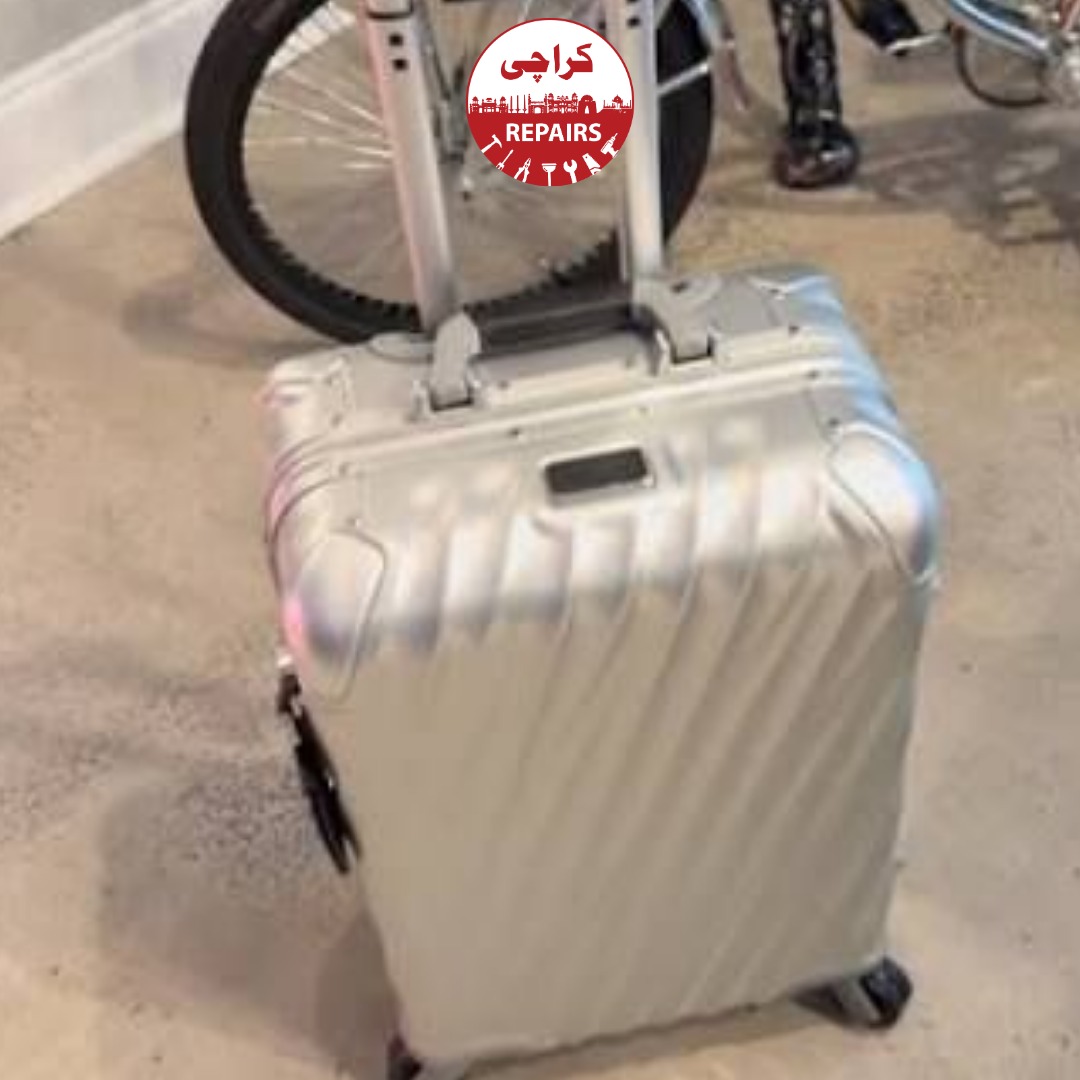 Technician extracting a broken wheel and telescopic handle from a Tumi suitcase in Karachi
