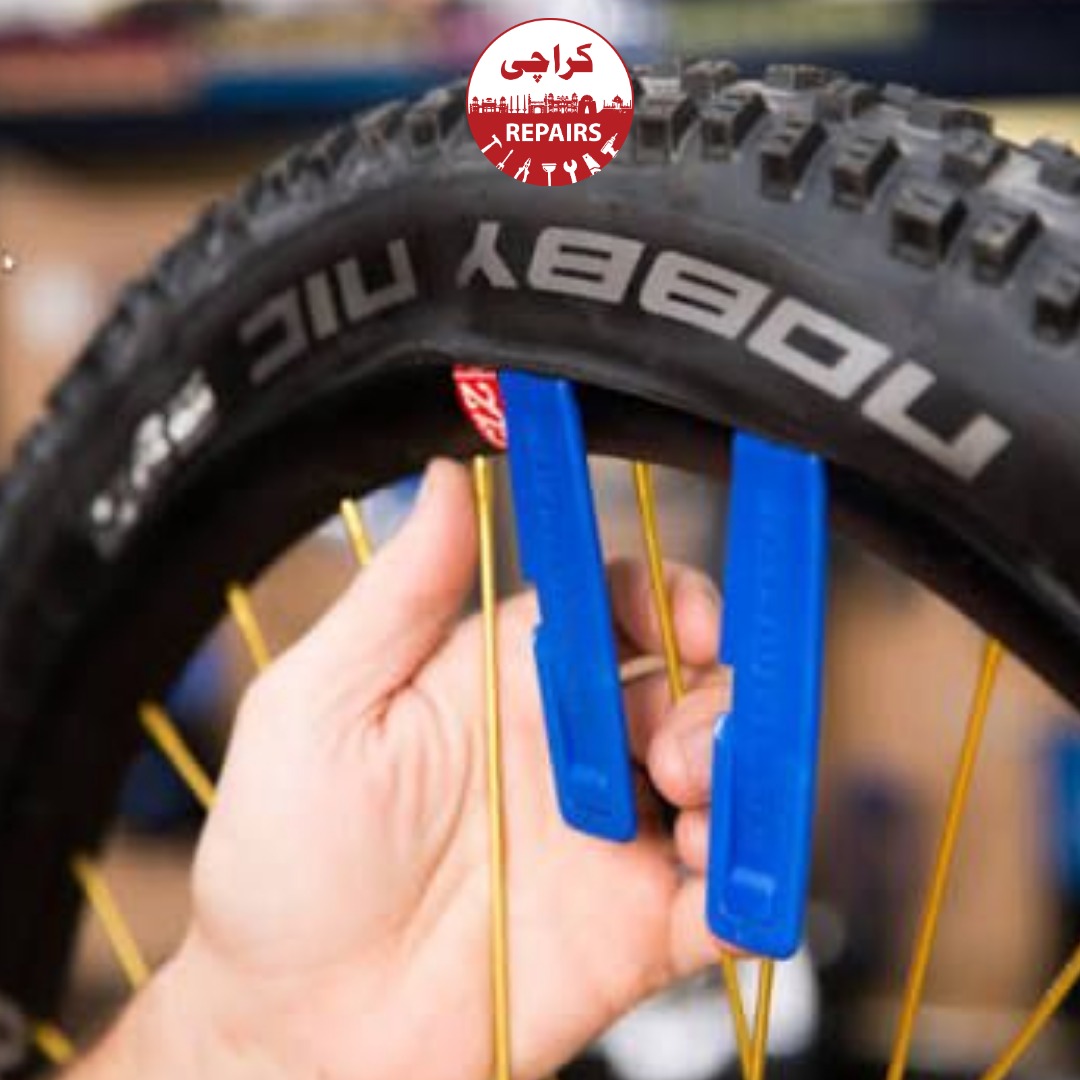 Expert bike mechanic carefully installing a new tire onto the wheel using smooth plastic tools